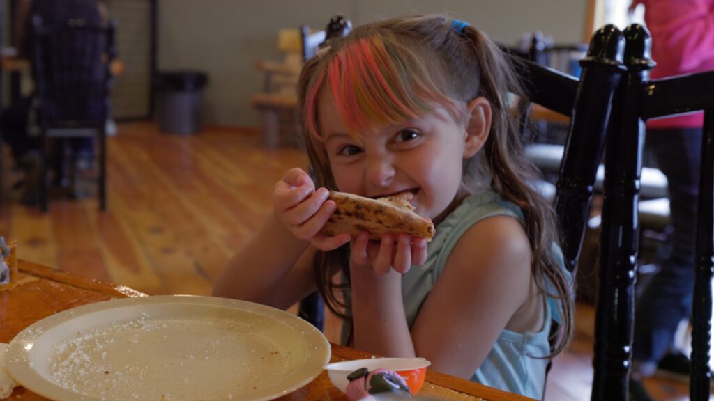 Girl enjoying a slice of pizza at Butte Brewing & Pizza Company in Butte, MT