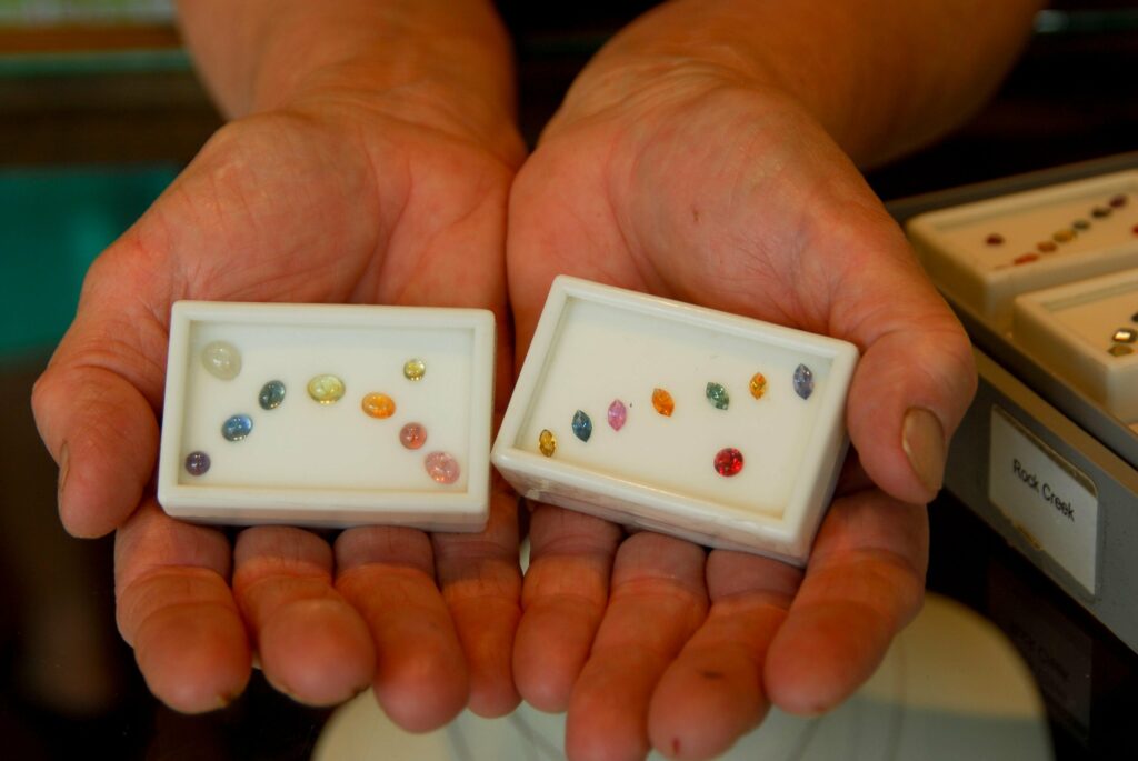 Box of Montana Sapphires showing the range in colors from cornflower blue sapphires to purple, pink, yellow and green Montana Sapphires.